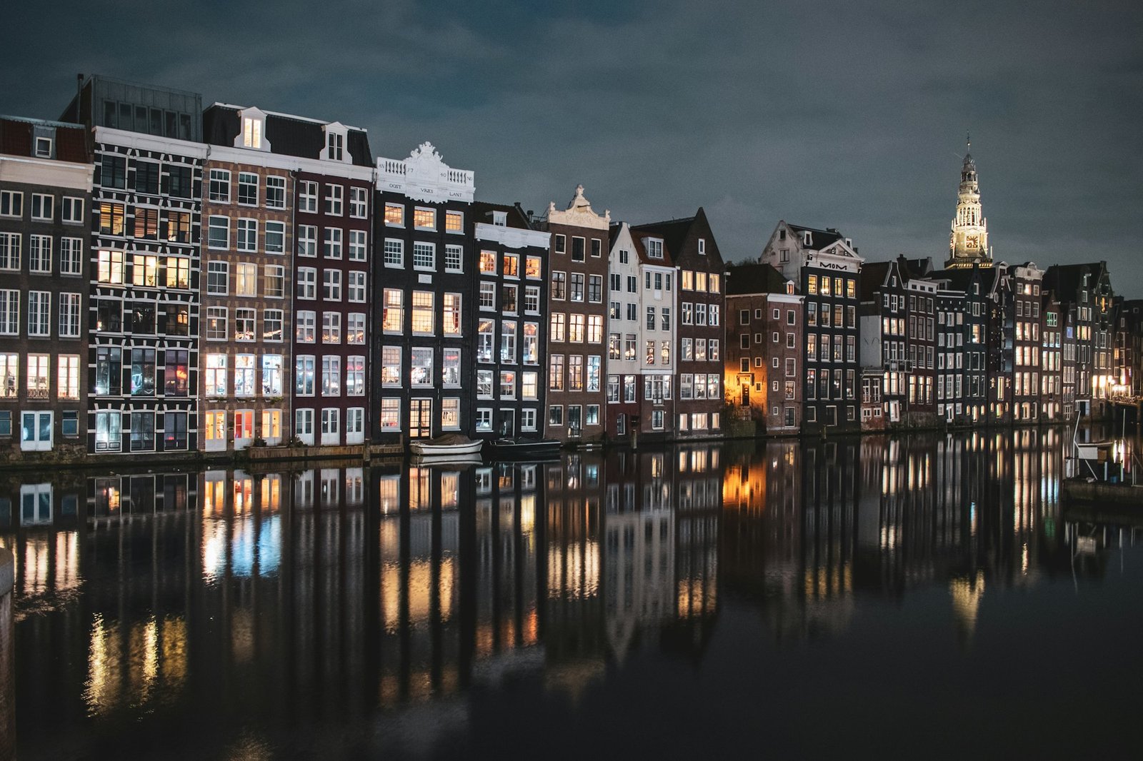 Amsterdam canal houses with warm lit windows reflected in the water at dusk