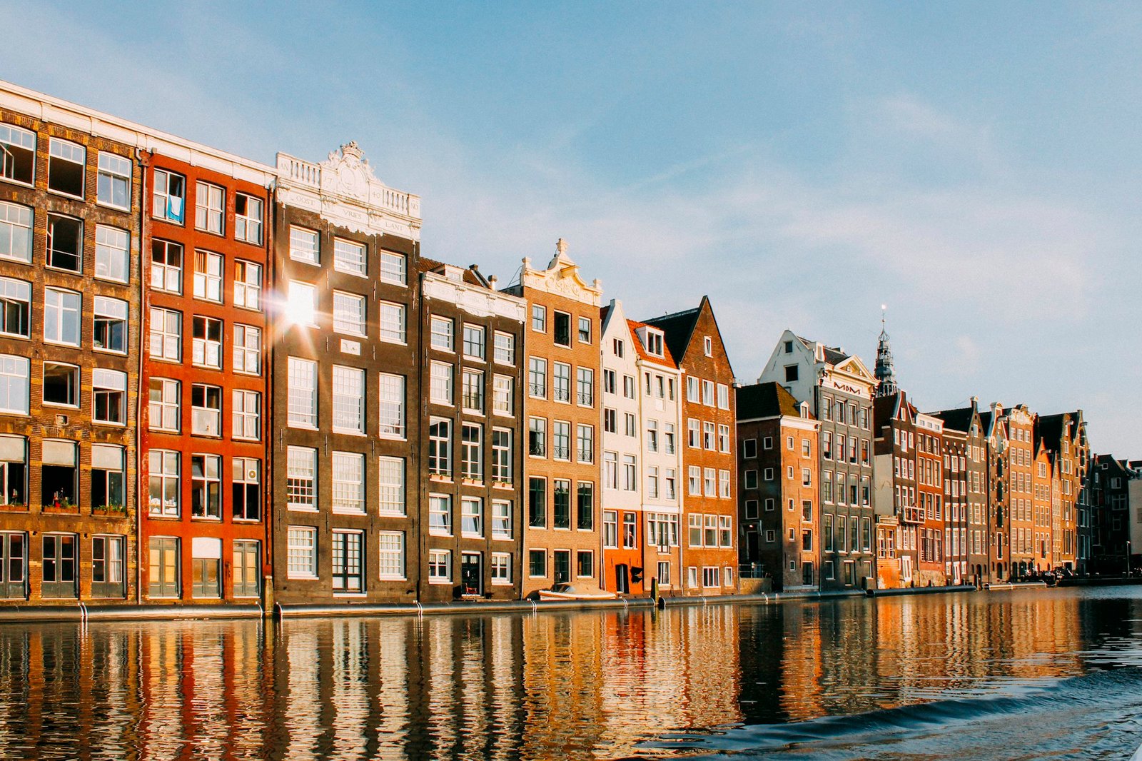 Row of colourful Amsterdam canal houses showing varied gable shapes, daytime