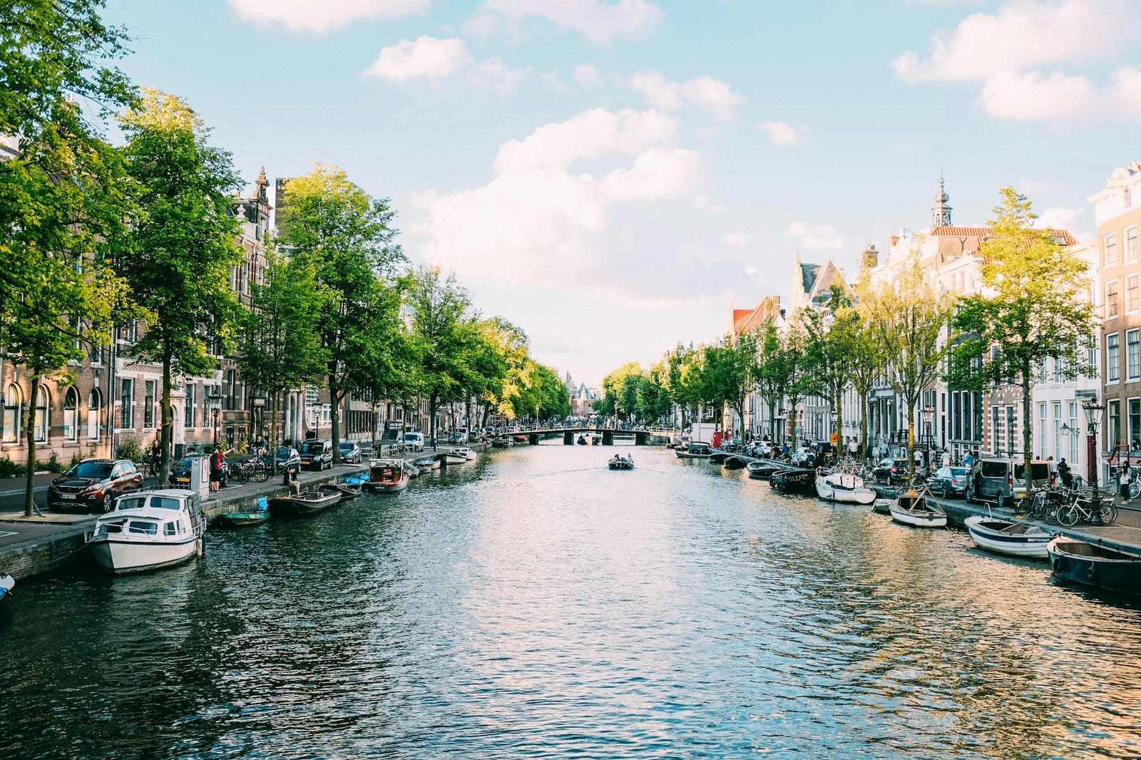 Quiet, tree-lined residential canal in Amsterdam, moored boats, no crowds