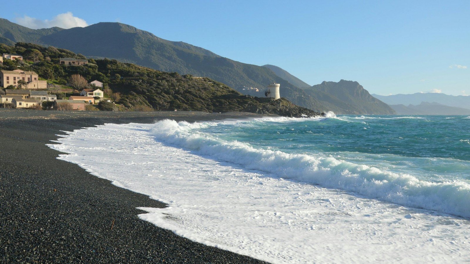 Round Genoese watchtower on a coastal headland above turquoise water
