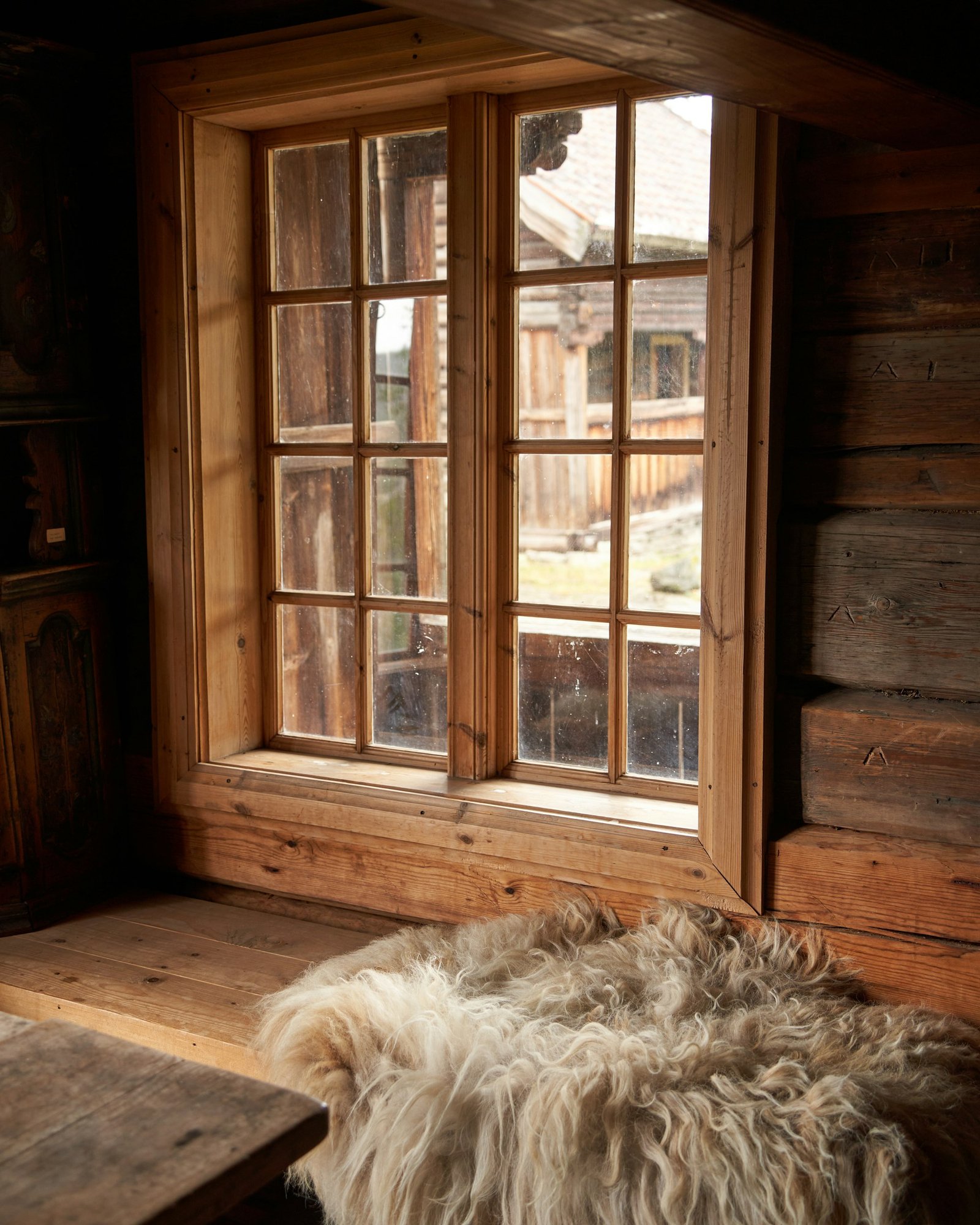 Traditional Nordic wooden interior with sheepskin and natural light, pale wood and worn, lived-in furnishings