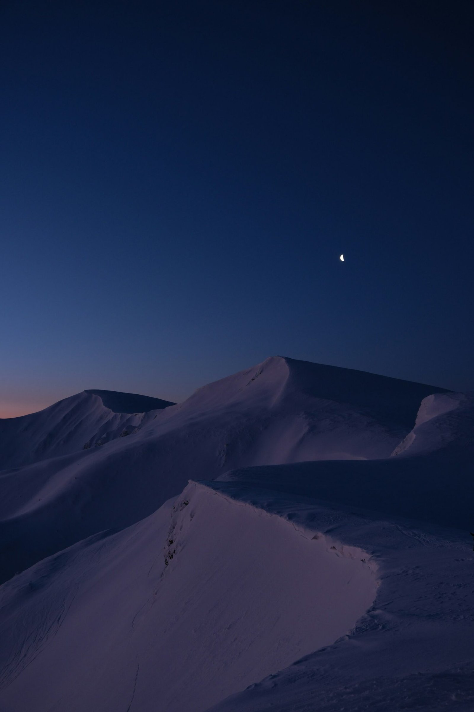 Winter daytime blue-hour light over snowy peaks, muted palette