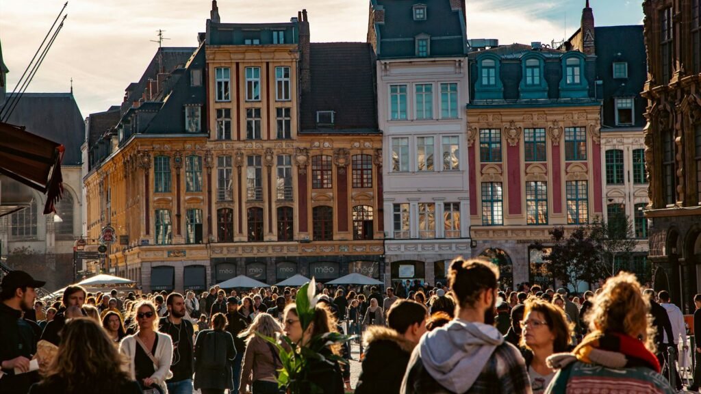 Dense crowd filling Lille's Grand-Place at sunset, Flemish facades behind