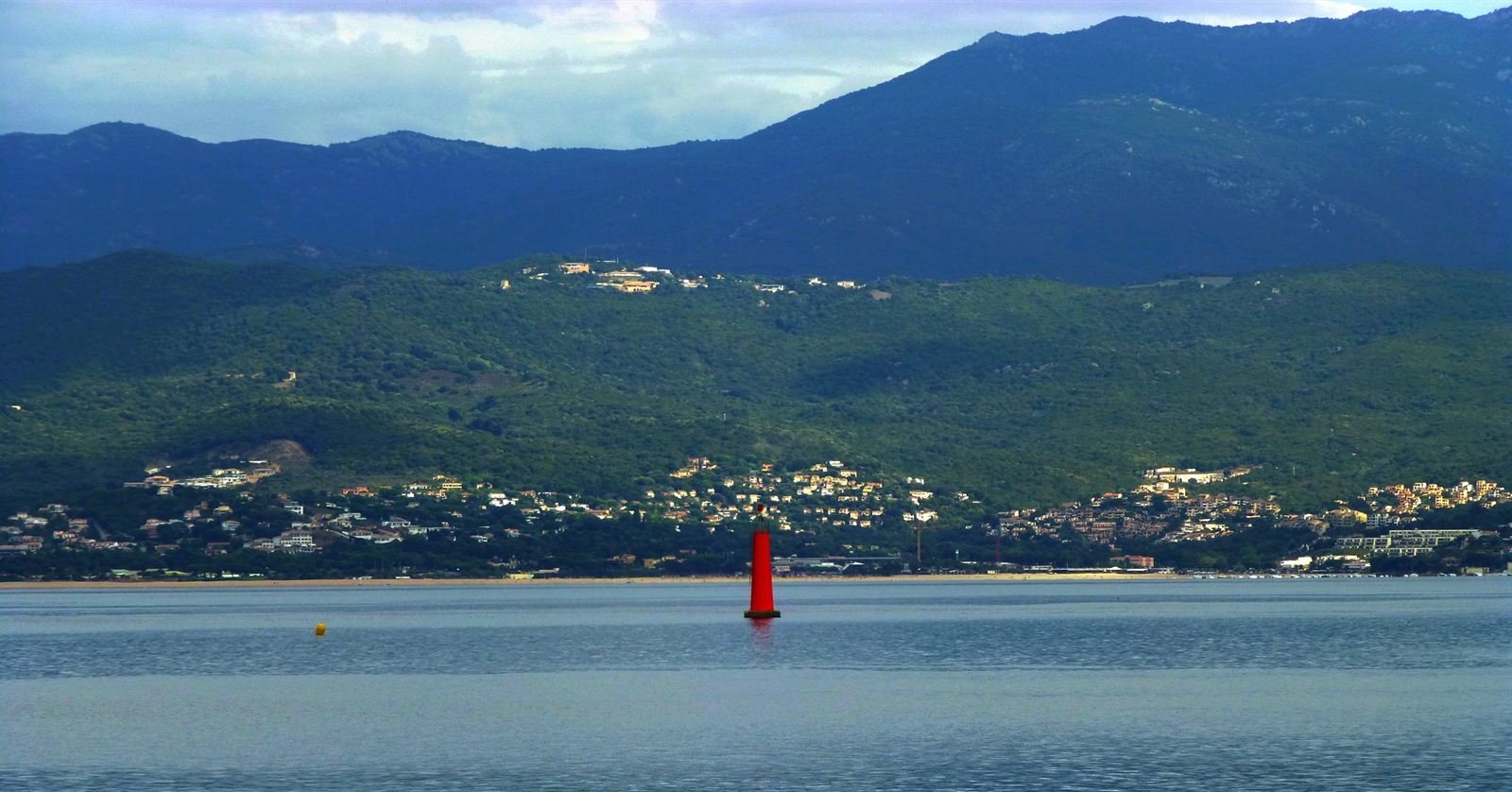 Scattered houses on wooded hills above the Gulf of Ajaccio, with mountains rising behind